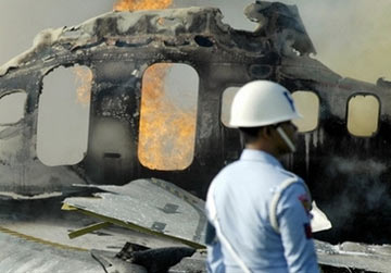 Một binh sĩ không quân Indonesia bên xác chiếc máy bay xấu số. Nó được cho là đã lao quá nhanh và trượt khỏi đường băng trước khi phát nổ và cháy. Ảnh: AFP.