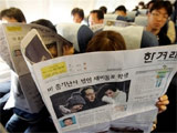 Hành khách Hàn Quốc đọc báo đưa tin vụ thảm sát trên máy bay.
